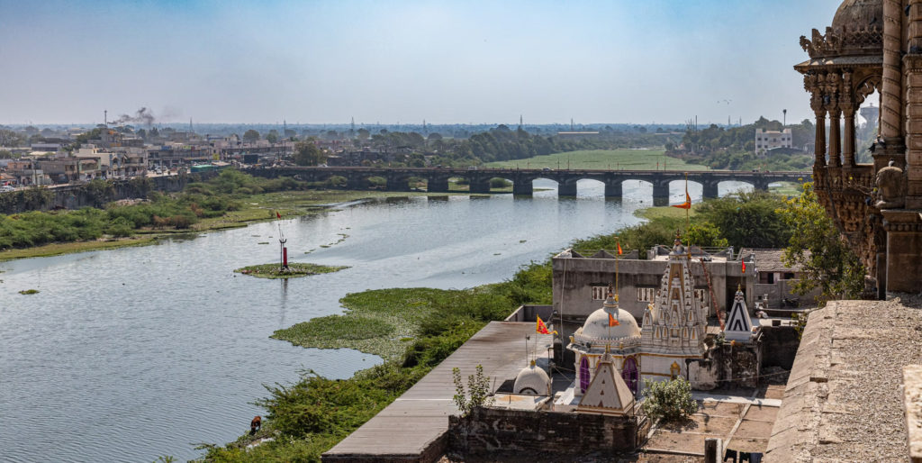 The Gondal River winds past temple spires and an old stone bridge near the royal palace complex