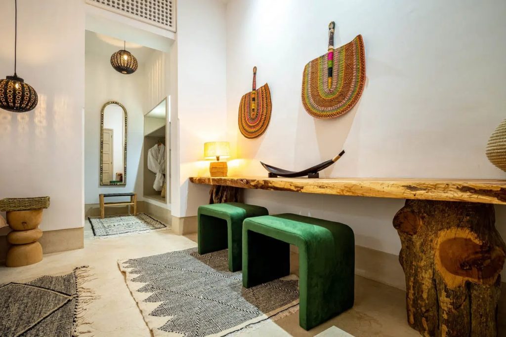 Corridor with woven wall fans, green velvet stools & a live-edge wood console table
