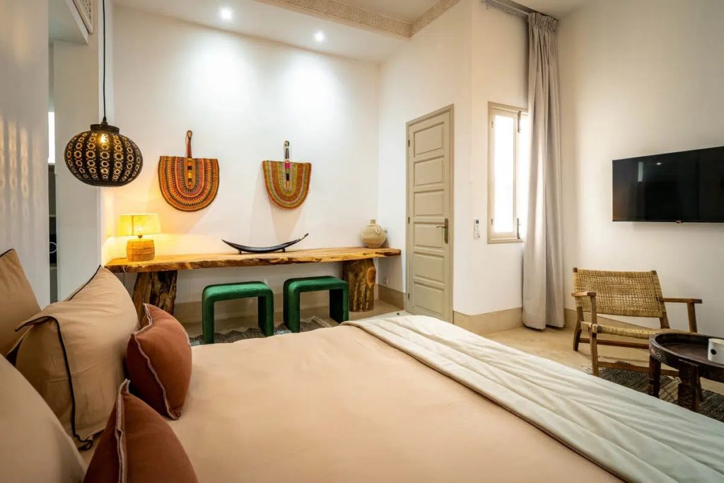 Bedroom with terracotta cushions, live-edge console & woven armchair beneath pendant lighting