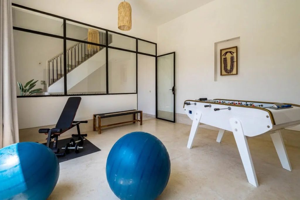 Gym with foosball table, exercise ball & weight bench behind a glass partition