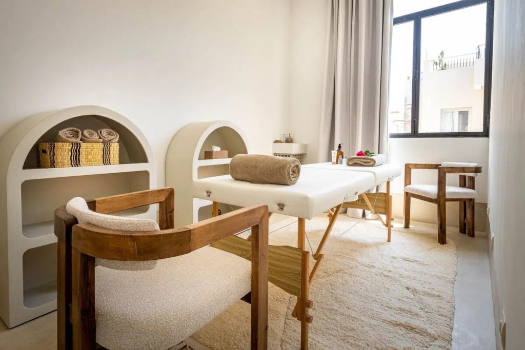 Spa treatment room with massage table, arched shelving & garden-view window