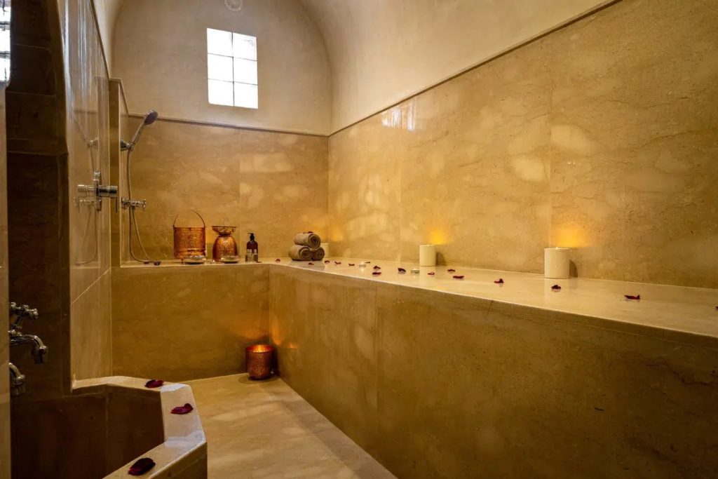 Traditional hammam with marble steam bath, copper vessels & rose petals