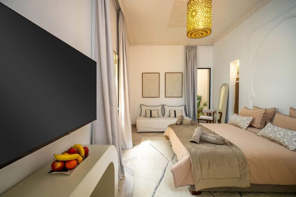 Bedroom with king bed, daybed & Moroccan pendant light beneath ornate ceiling detail