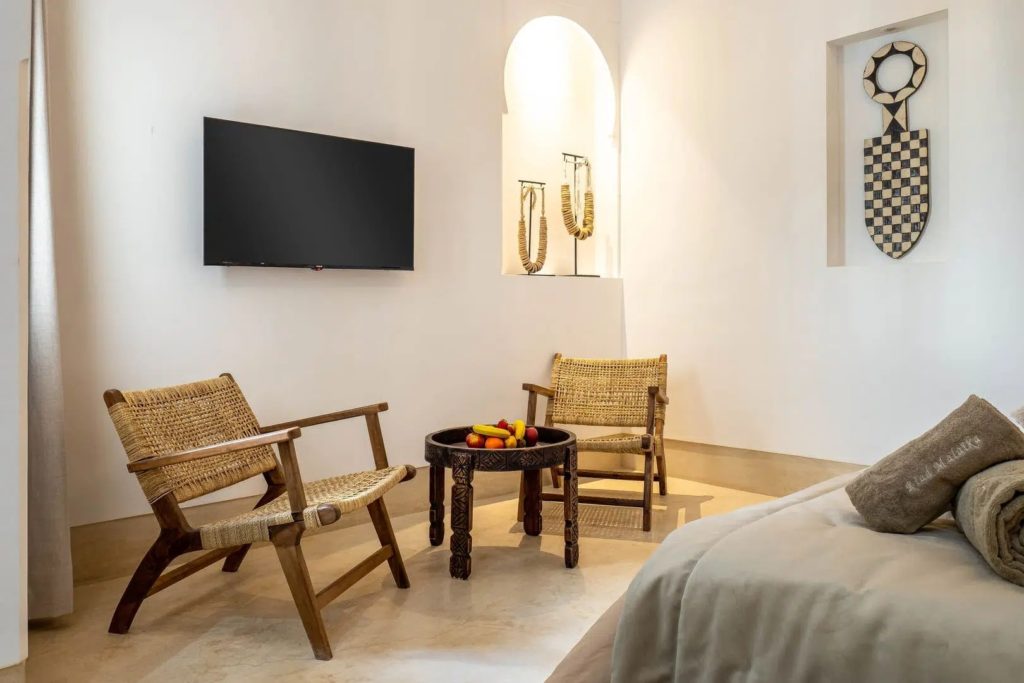 Seating area with woven armchairs, carved side table & wall-mounted artefacts