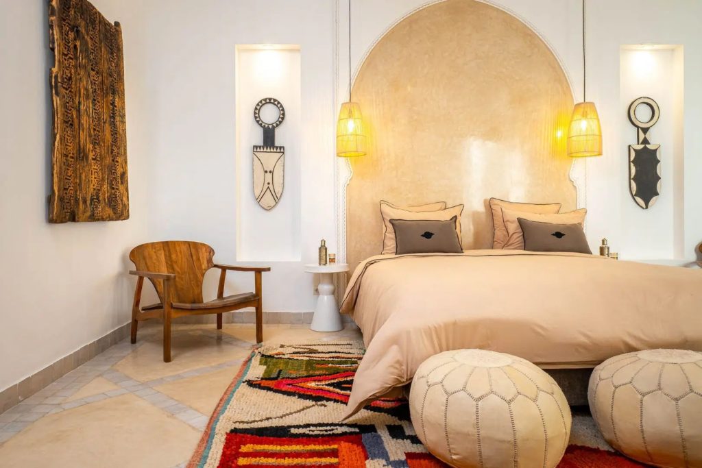 Bedroom with arched headboard, woven pendant lamps & Moroccan poufs