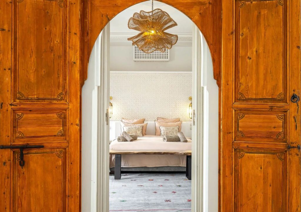 Carved wooden doorway opening onto a bedroom with live-edge bed frame