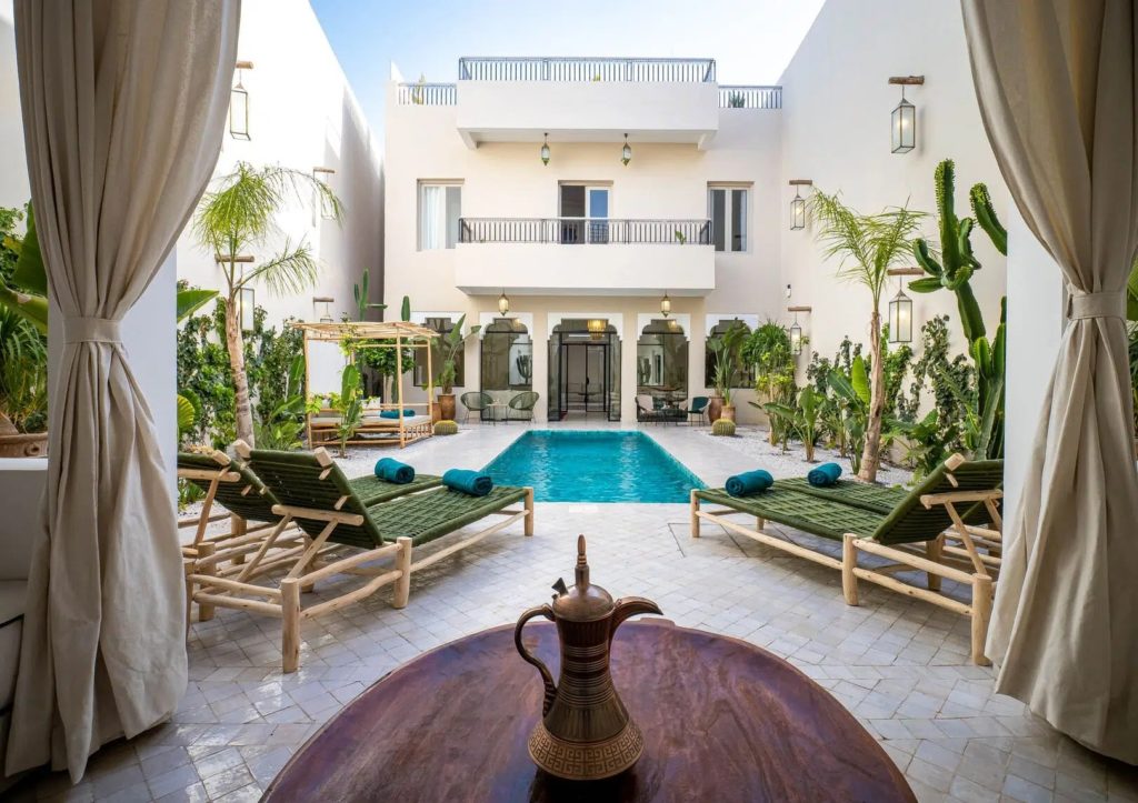 Courtyard pool framed by loungers, palms & the riad's arched façade