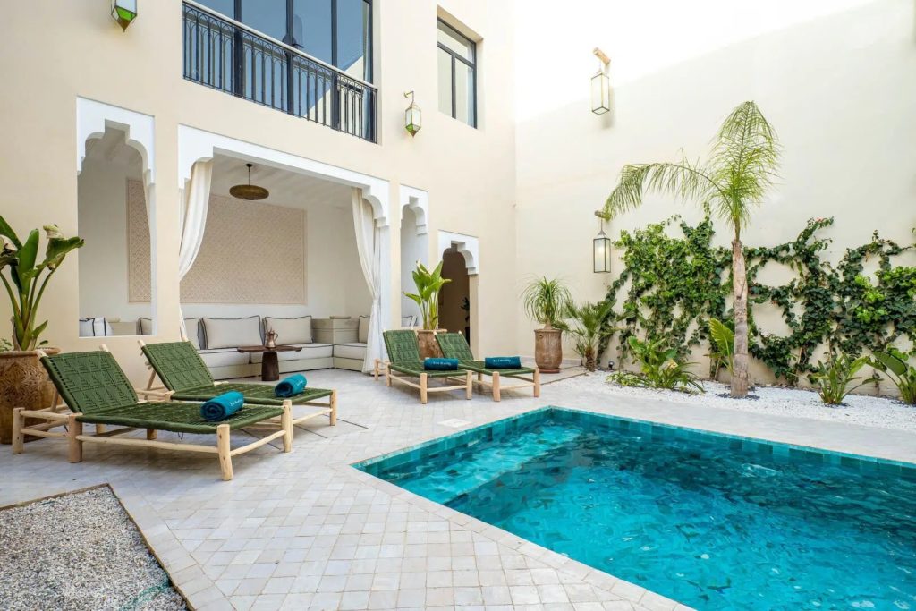 Poolside terrace with lounge chairs, cacti & climbing greenery against the courtyard wall