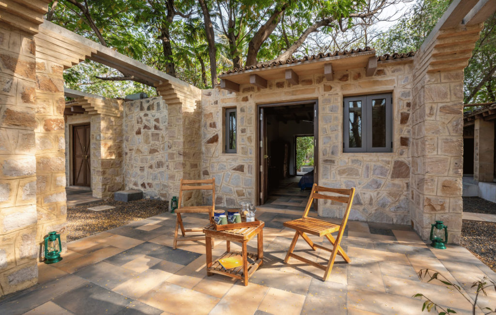 Stone-walled courtyard entrance to a Safari Cottage, with folding chairs set out for morning tea.