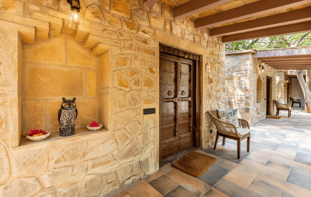 Stone archway entrance to a guest cottage, with a carved wooden owl ornament set into the wall niche.