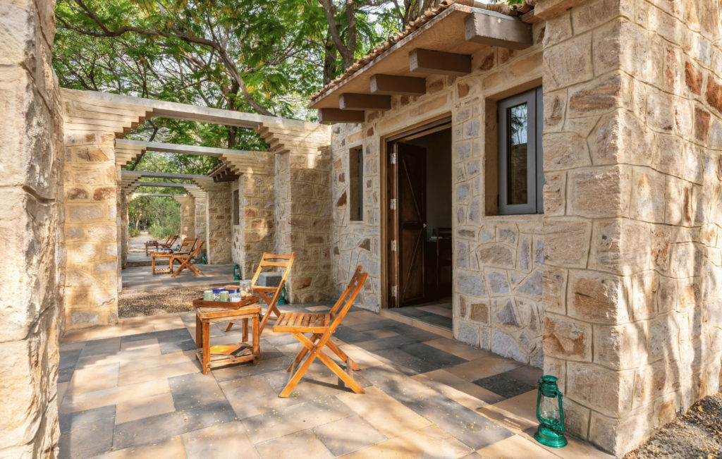Colonnade of stone-walled cottages with private terraces set beneath shade trees at Rann Riders.