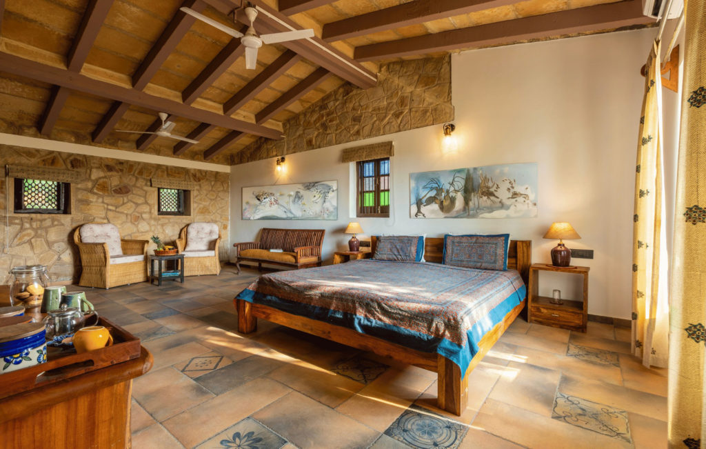 Dasada Premium Wing bedroom with vaulted stone ceiling, wildlife artwork and a richly patterned bedspread.