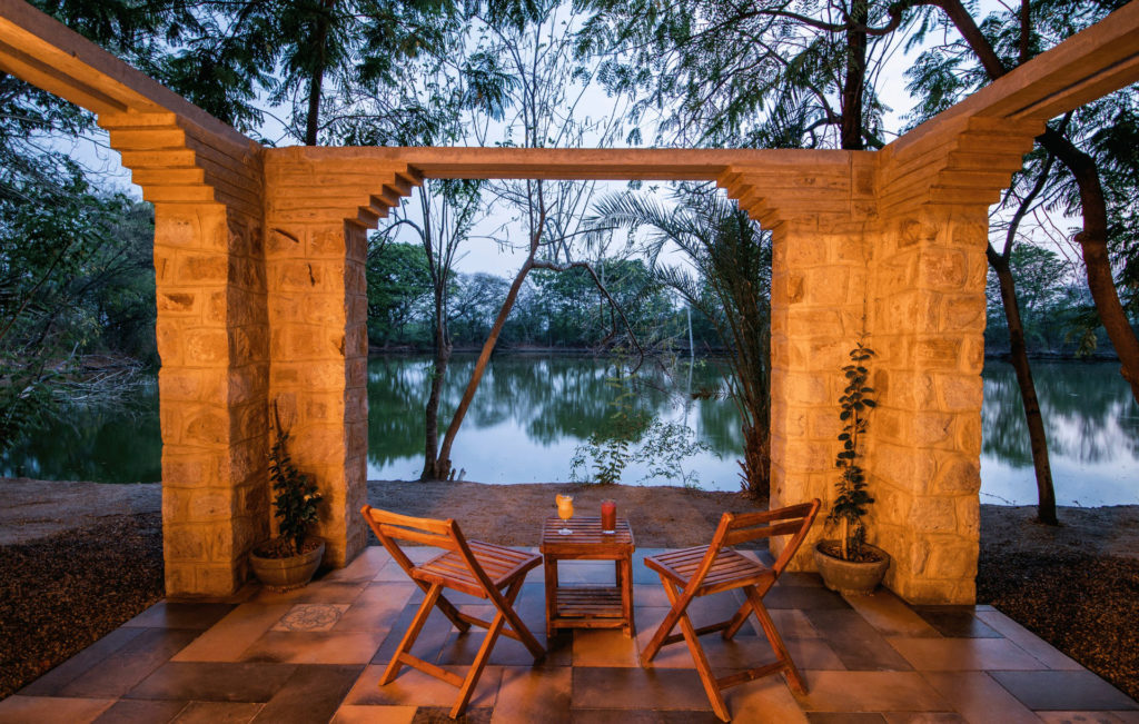 A private terrace at dusk with two cocktails set out beneath a stone archway overlooking the lake.
