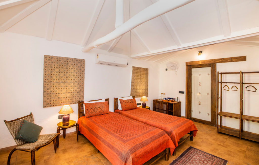 Twin-bedded Bhunga cottage room with white vaulted ceiling and traditional block-printed bedspreads.