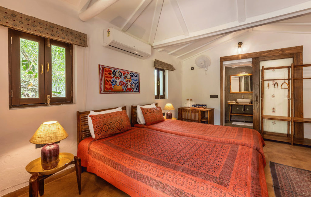 Bhunga cottage bedroom with an en-suite bathroom visible through the doorway and block-printed textiles.