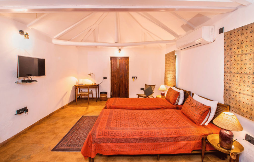 A twin-bedded Kooba cottage room in warm terracotta tones, with block-printed textiles and a private terrace.