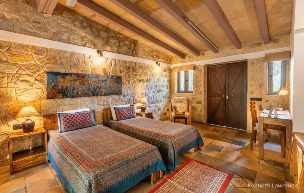 Twin beds with block-print linens in a stone cottage at Rann Riders Resort