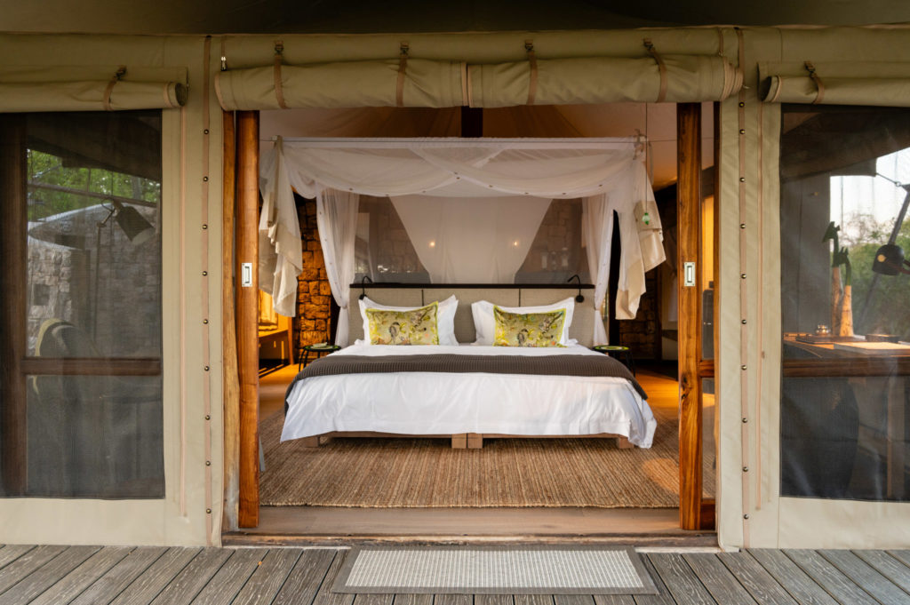A luxury tented suite with a four-poster bed opening onto a private deck