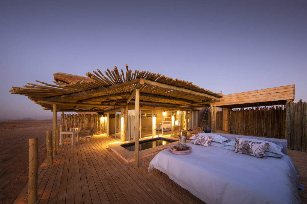 A private plunge pool and daybed on a desert lodge deck at dusk