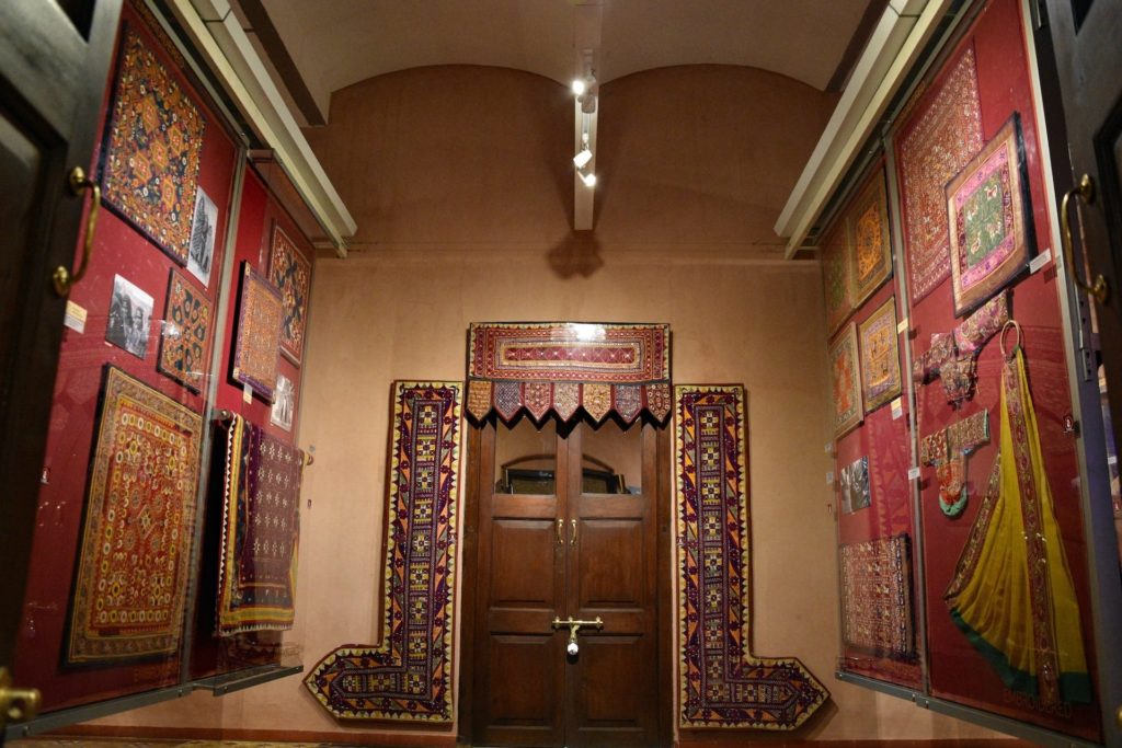 Display of framed embroidered Kutch textiles lining a museum-style corridor