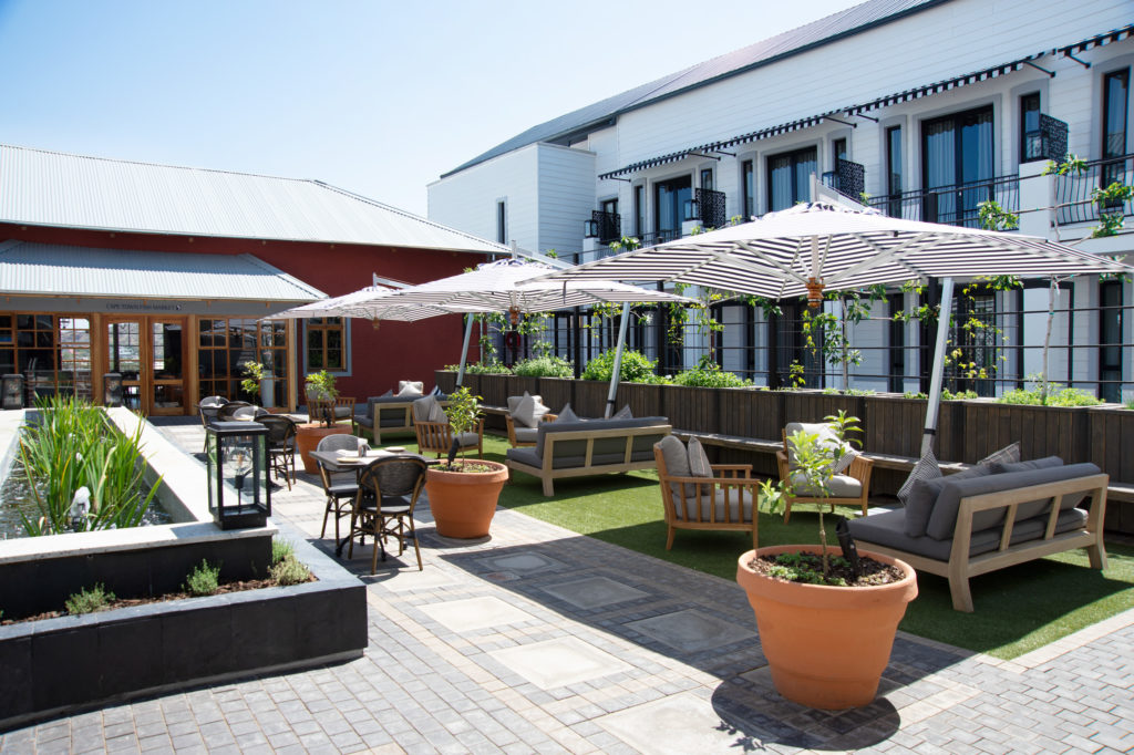 Courtyard lounge at The Weinberg with striped umbrellas, potted trees and views of the guest room balconies above