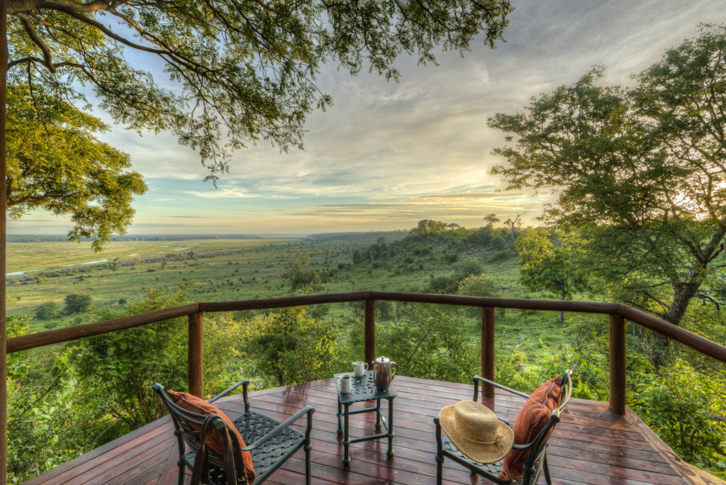 Morning coffee on a private cottage deck at Muchenje Safari Lodge, with a sweeping panorama of green woodland and the silver thread of the Chobe River in the distance.