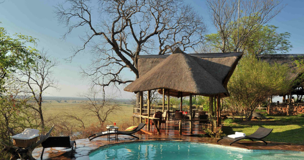 The swimming pool and thatched main deck at Muchenje Safari Lodge, with sunloungers beside the pool and an open view over the floodplains to the Chobe River beyond.