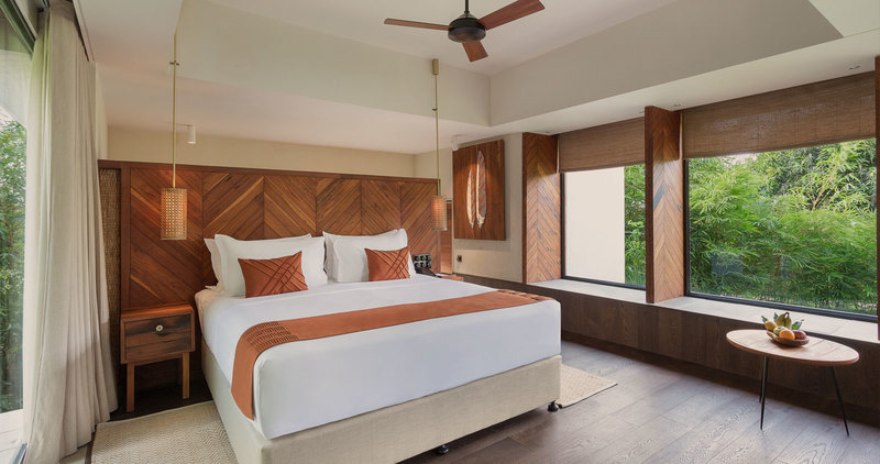 A wood-panelled bedroom with garden views at Woods at Sasan Gir
