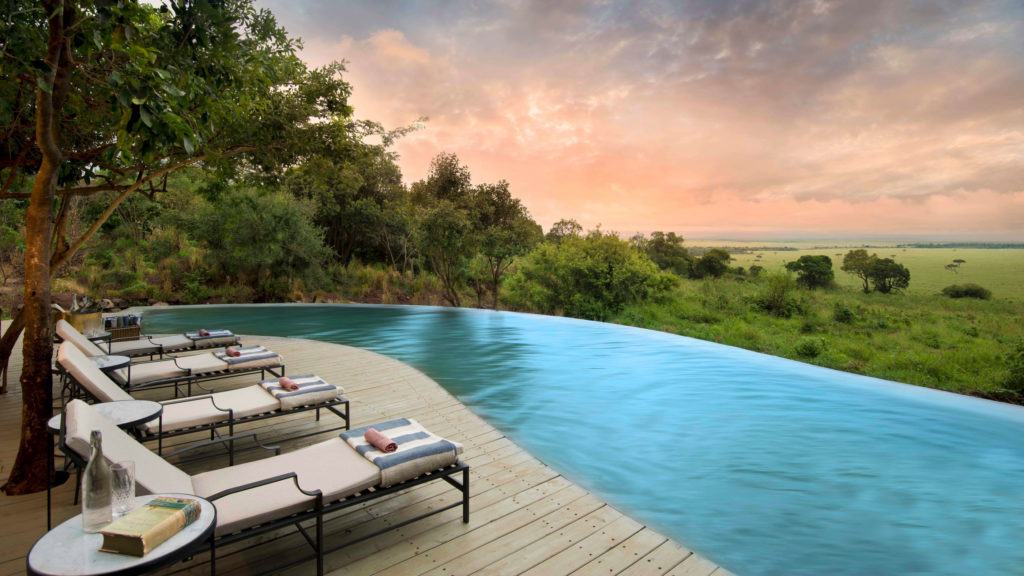 Sun loungers line an infinity pool overlooking the forest and plains as evening light fades