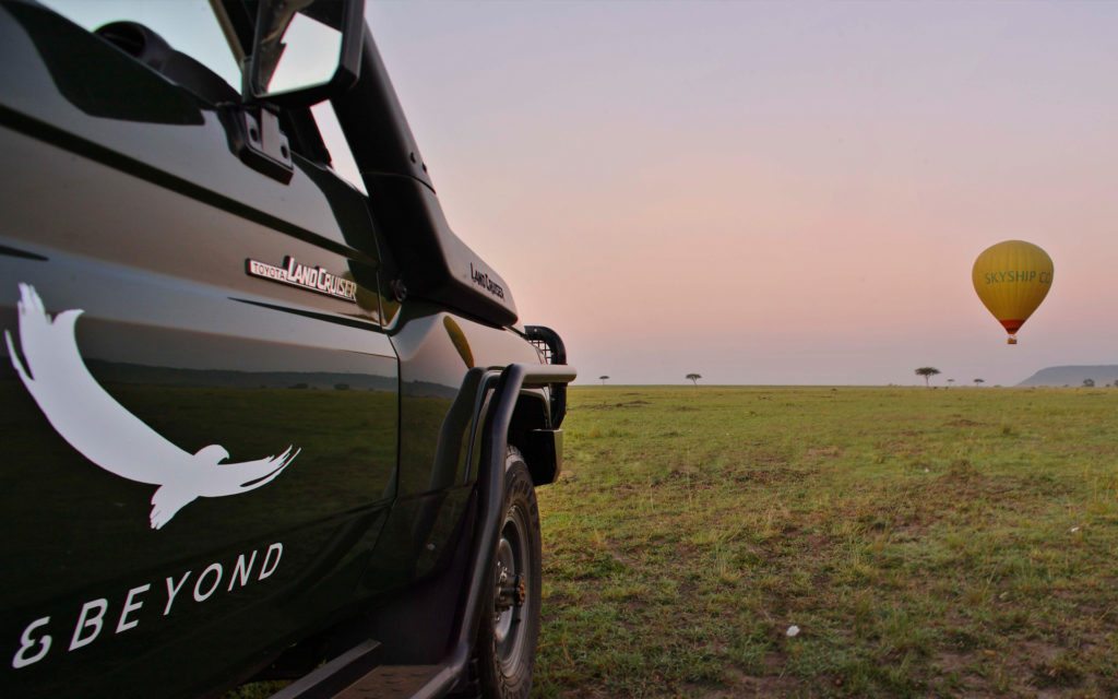 A hot air balloon drifts over the plains near Bateleur Camp at sunrise
