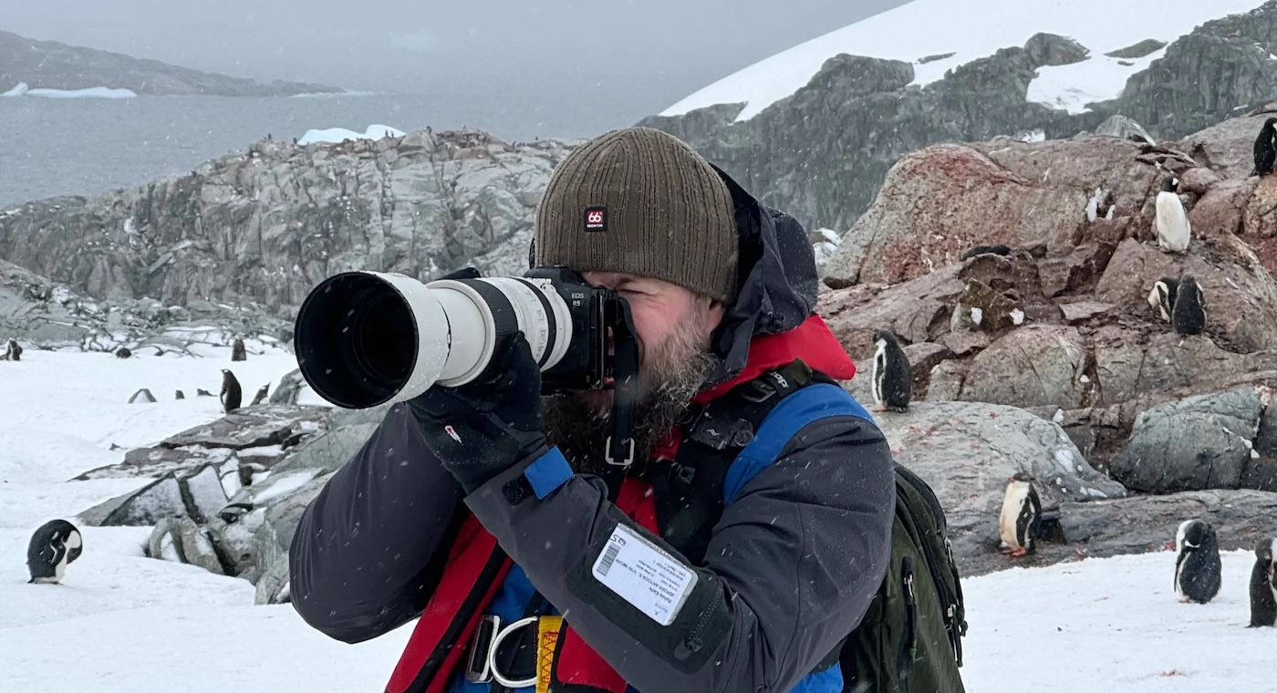 Photographer in Antarctica surrounded by penguins