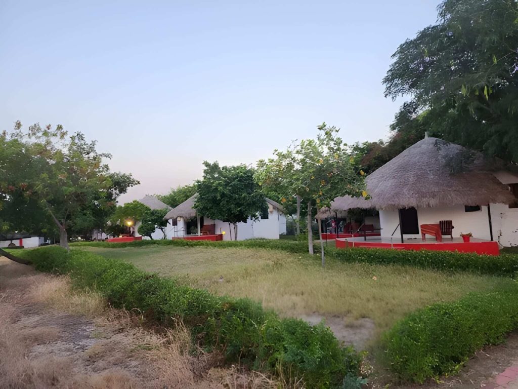Thatched cottages and lawn at dusk with a red-stepped terrace