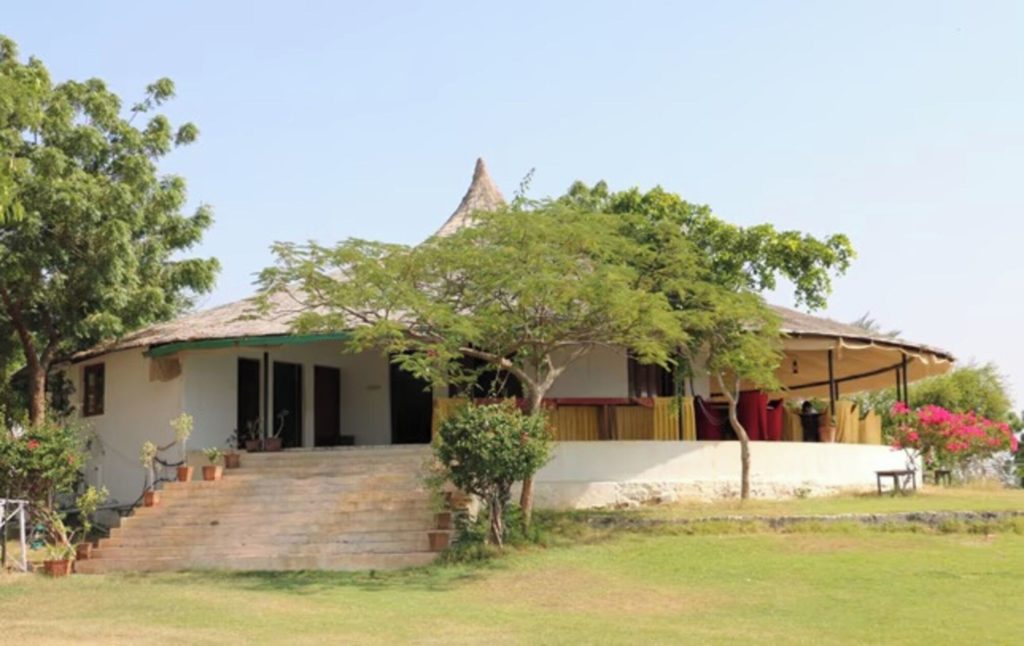 Round bhunga cottage with wraparound thatched veranda on the hilltop lawn