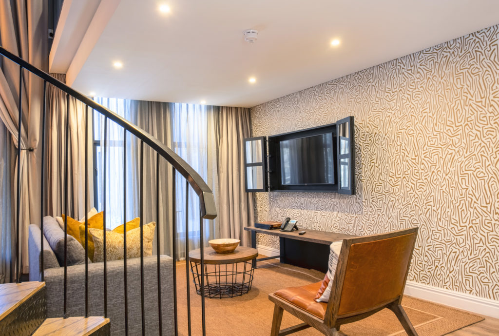 Loft lounge area at The Weinberg with spiral staircase, patterned feature wall and wall-mounted television