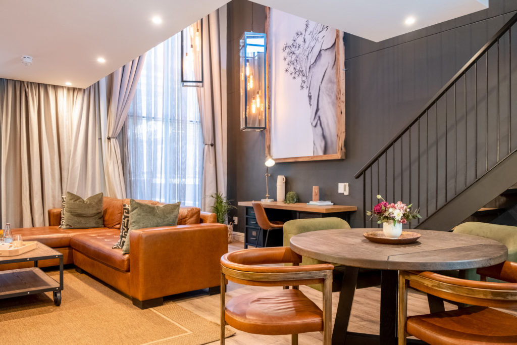 Loft living and dining area at The Weinberg with leather sofa, round dining table and staircase to the upper level