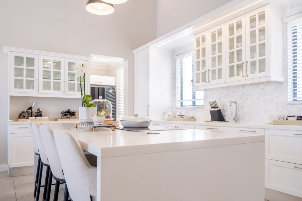 Open-plan kitchen at The Weinberg Windhoek with white cabinetry, marble splashback and central island seating