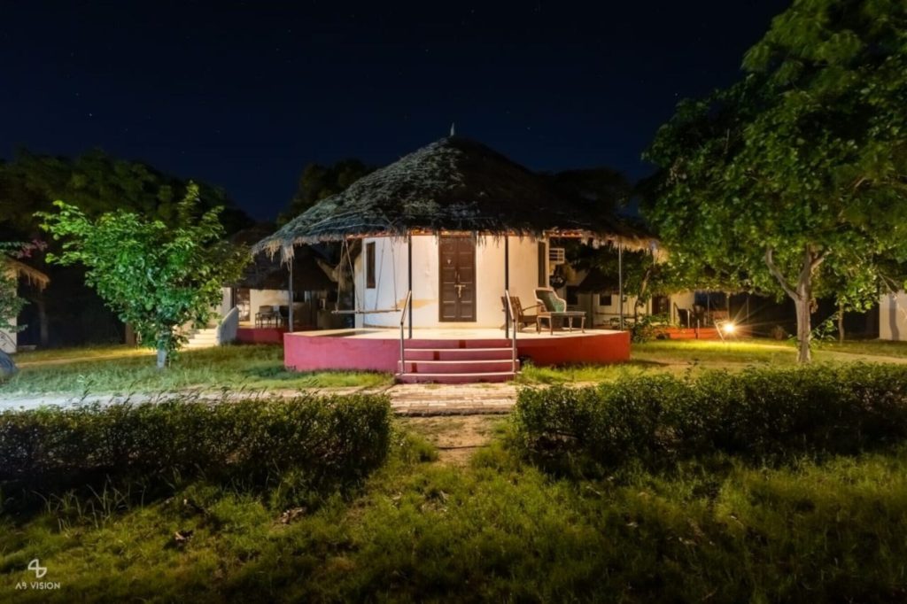Bhunga cottage lit at night beneath a starlit sky