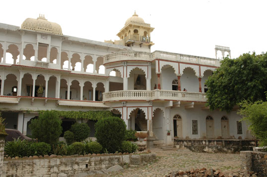 Tiered stone arches and balustraded balconies wrap the heritage facade of Darbargadh Poshina beneath a golden domed cupola