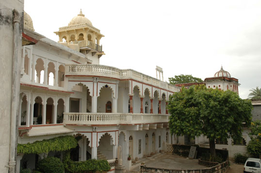A golden-domed turret rises above the arched balconies of Darbargadh Poshina, with a second smaller cupola visible in the distance