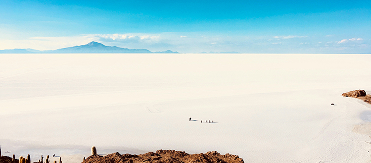 An expansive view of Bolivia's Uyuni salt flats with a group of walkers dwarfed by the impressive scenery
