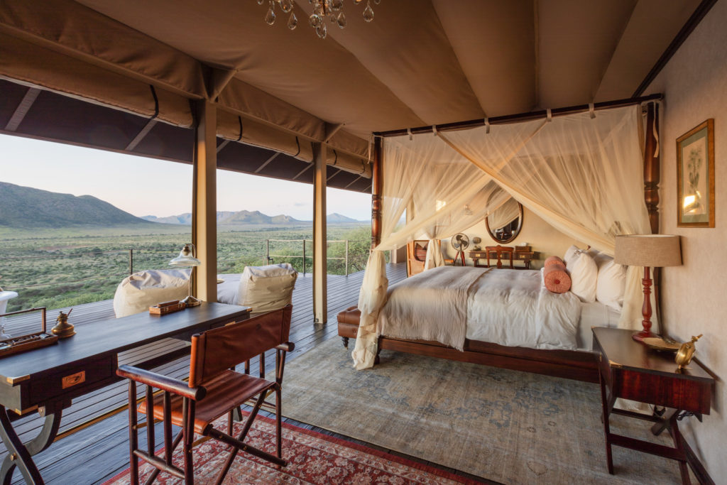A four-poster bed draped in mosquito netting overlooks the Khomas Plateau