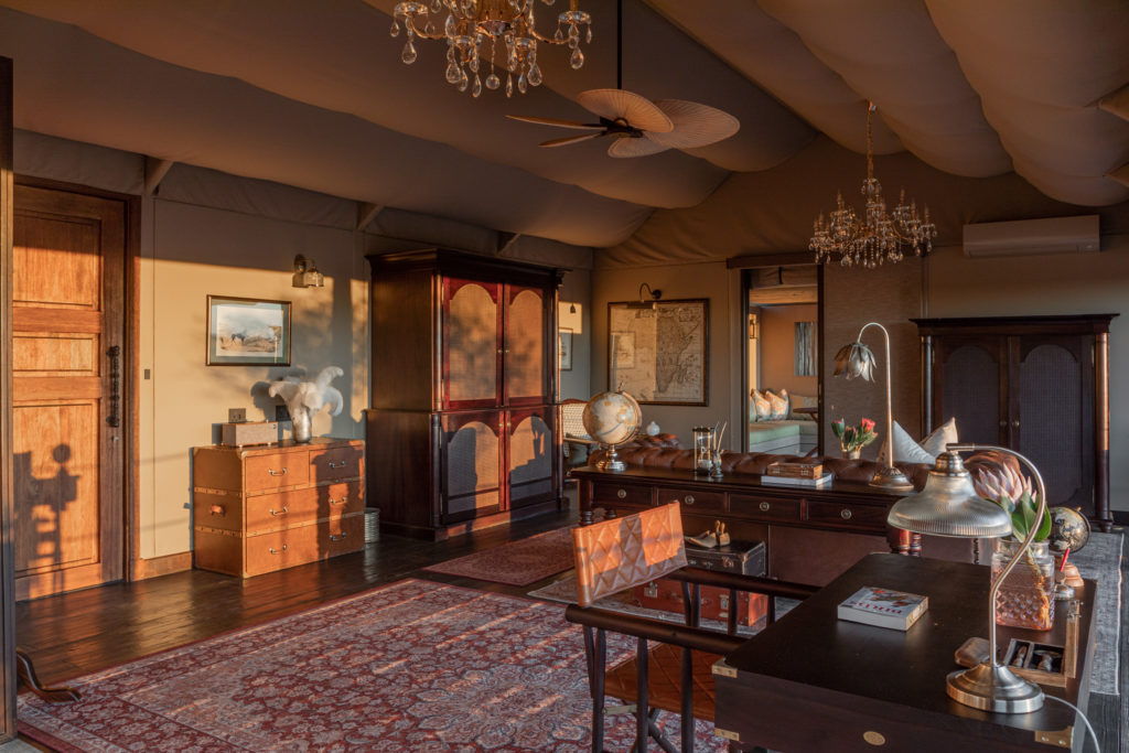 Antique cabinetry, a globe and safari curios furnish a suite's sitting area at Gmundner Lodge