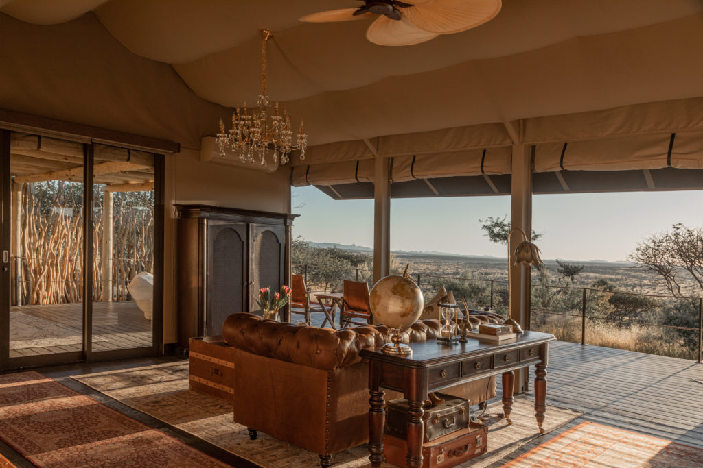 A leather chesterfield sofa faces sweeping desert views from the suite's open-sided lounge