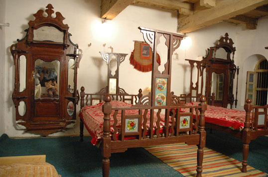 An antique four-poster bed and ornate carved mirror in a heritage-furnished bedroom at Darbargadh Poshina