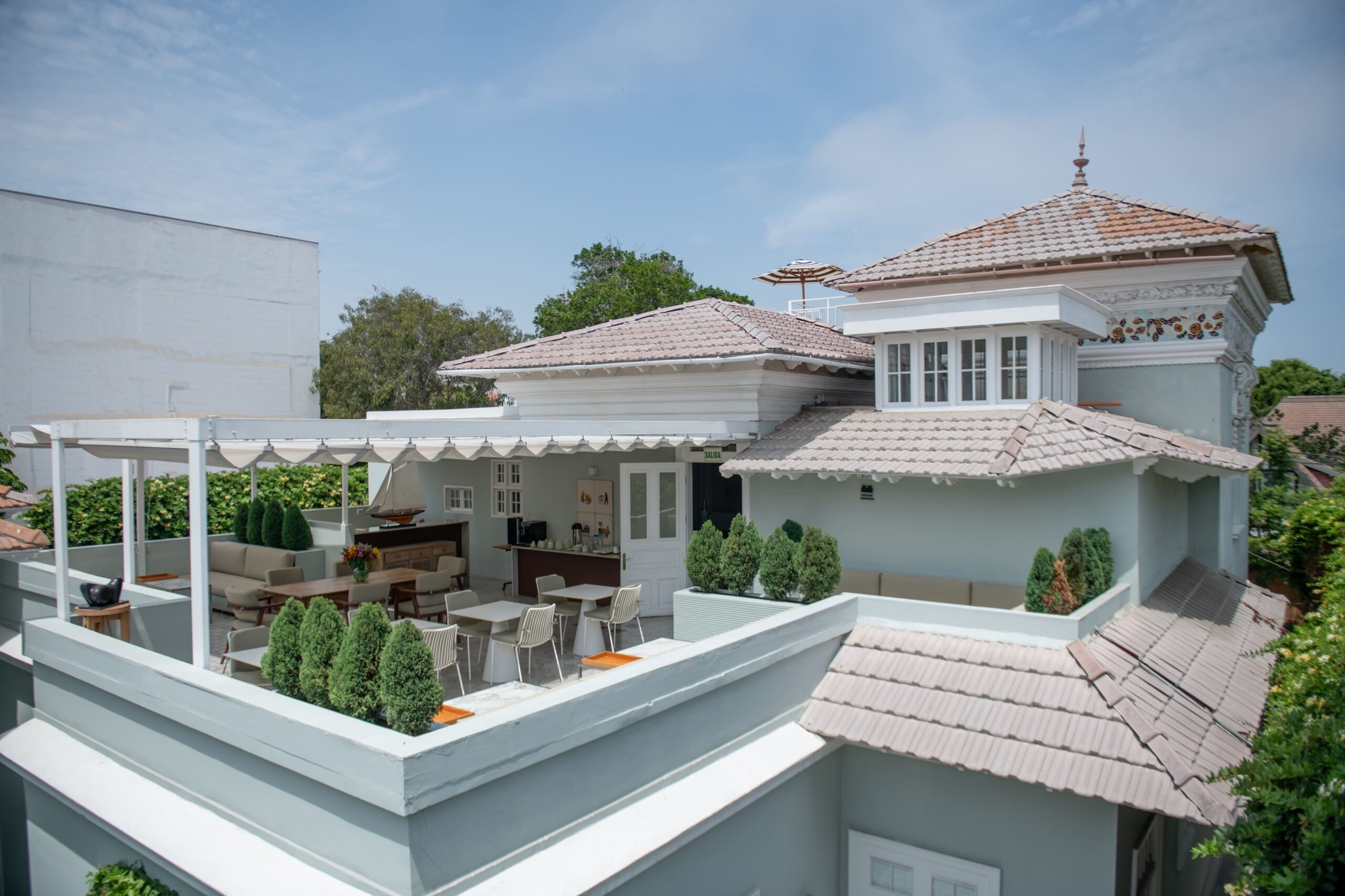 Rooftop terrace with a pergola, potted conifers and outdoor dining set beneath the mansion's tiled turret