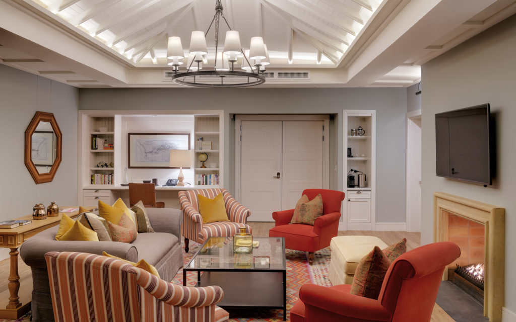 Lounge area of the Presidential Suite at Strand Hotel Swakopmund with a vaulted ceiling, fireplace, built-in library nook and striped armchairs